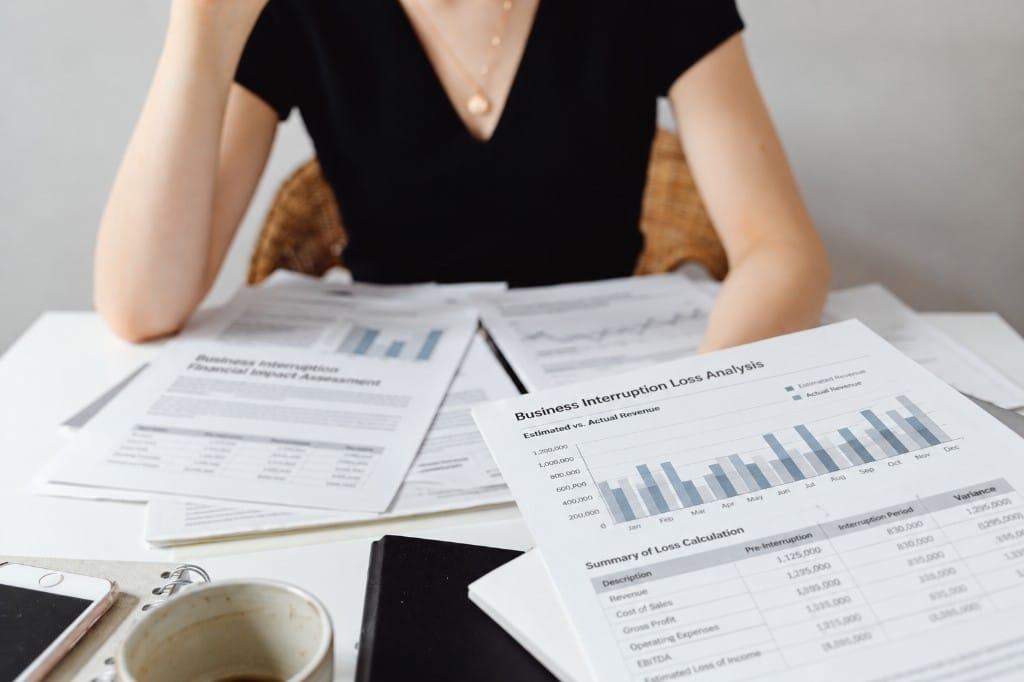 Business interruption loss analysis papers comparing estimated and actual revenue on a desk