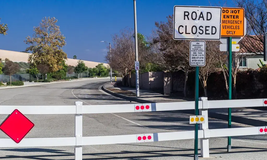 A road closed sign and barrier across a street