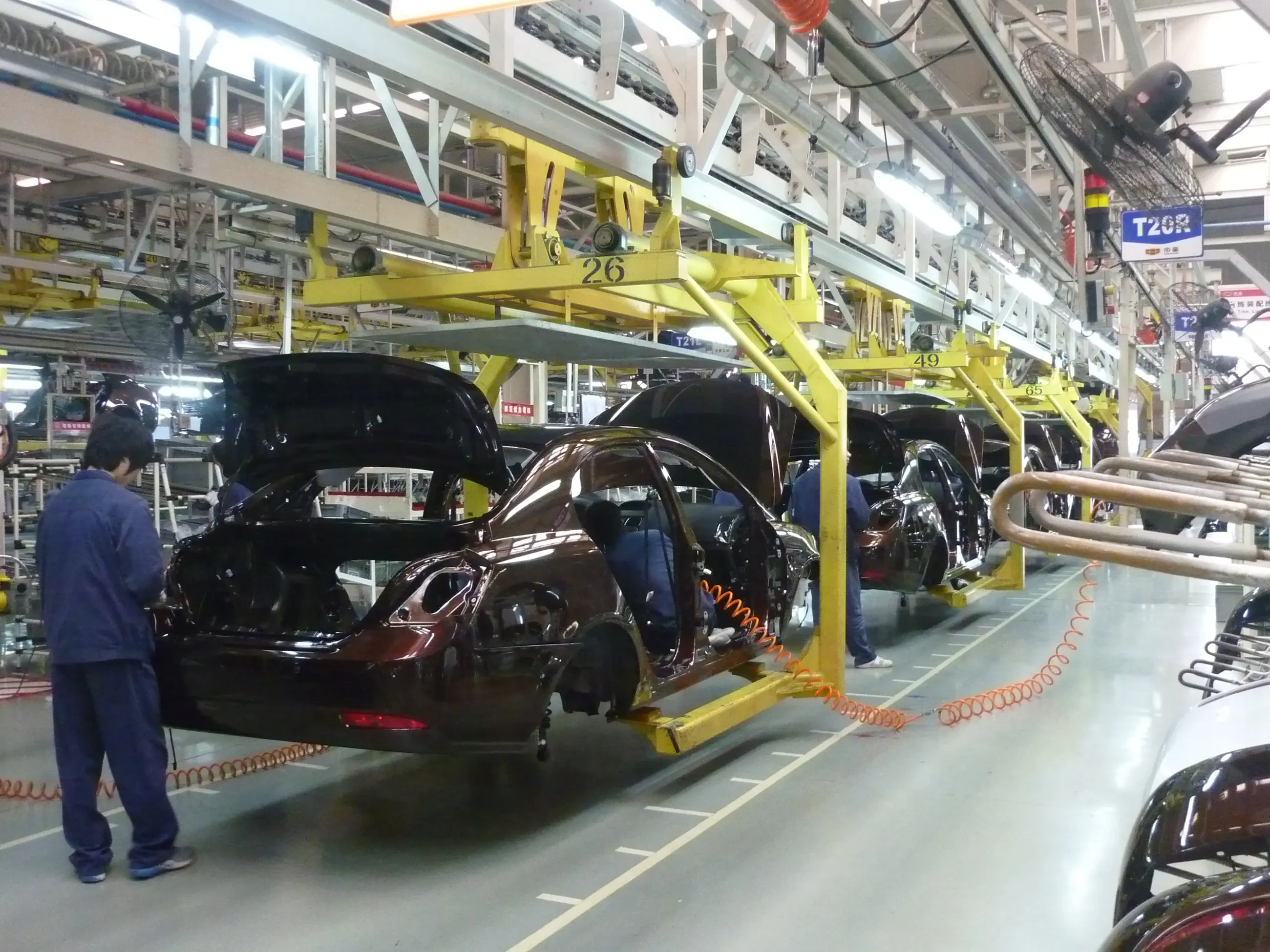 Cars moving along an assembly line with a worker beside them